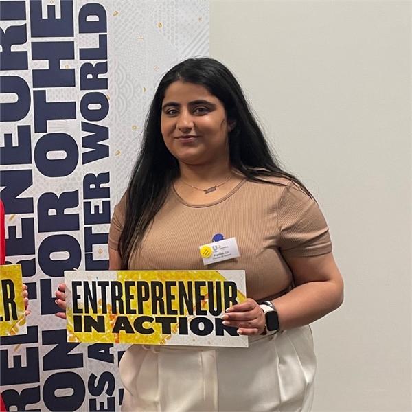 Pravjoth is smiling at the camera whilst holding a banner that says Entrepreneur in action