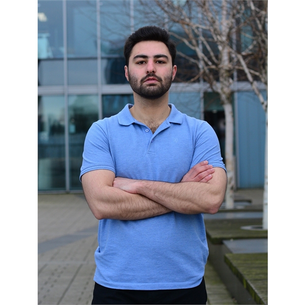 Asad is in a light blue shirt with his arms crossed looking straight to the camera
