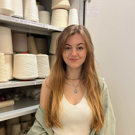 Eleanor is smiling within a textiles resouce cupboard