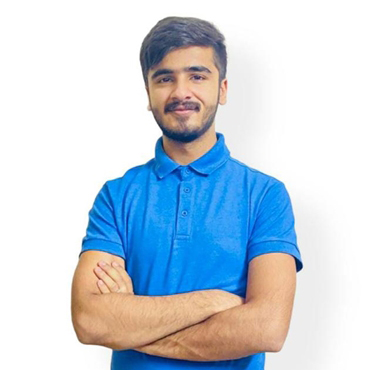 Emad smiling to camera, crossing his arms whilst wearing a blue shirt