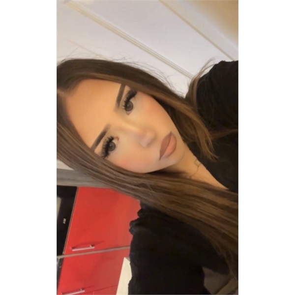 Nabila has long brown hair and is wearing a black top