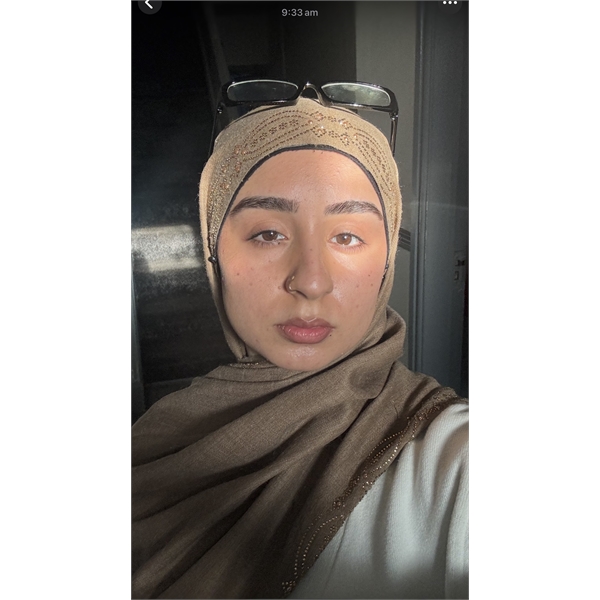 Tanzila has a beige and cream coloured hijab on with glasses on top of her head