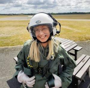 Dr Lily is wearing a fighter pilot suit with a helmet whilst wearing glasses